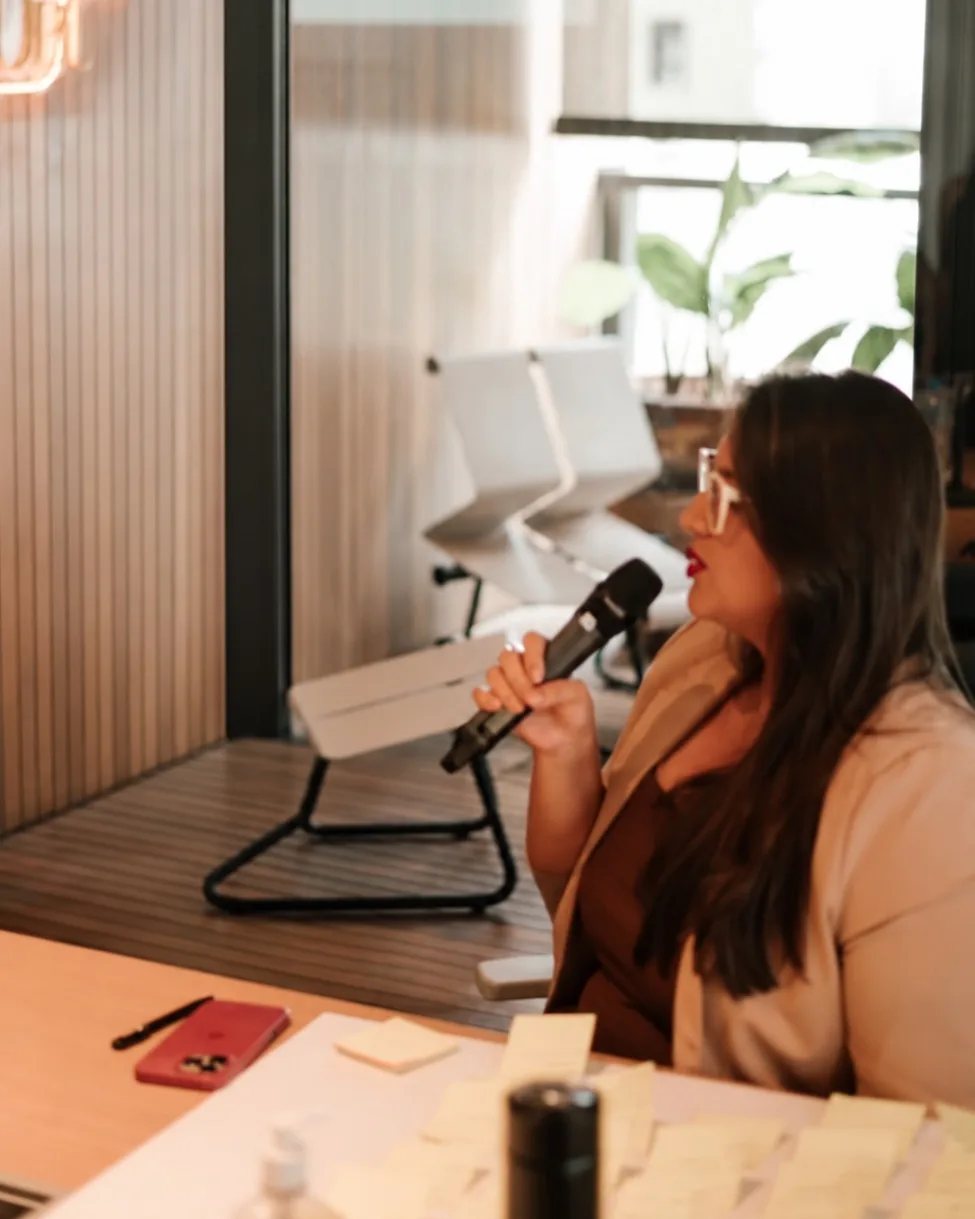 Cláudia Braz com microfone na mão, conduzindo um encontro da mentoria