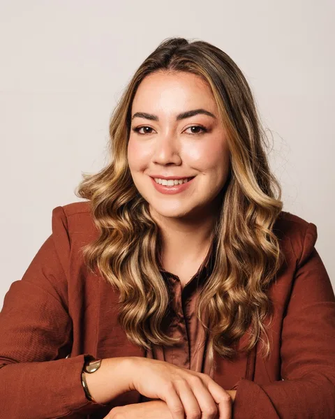 Jemima Campos, mentorada, sorrindo com os braços apoiados no encosto de uma cadeira
